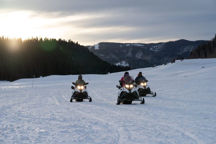 a group of people riding snowmobiles on a trail