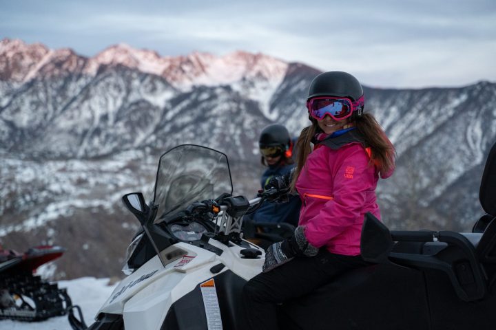 two people sitting on snowmobiles